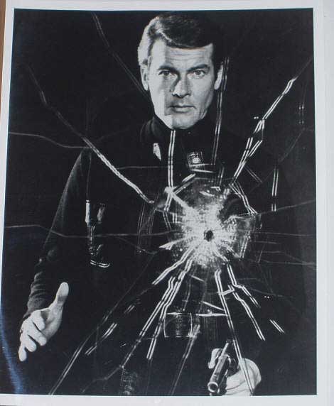 LIVE AND LET DIE (James Bond): B/W Still (Roger Moore Shoots Glass)